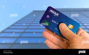 main tenant une carte bancaire devant banque