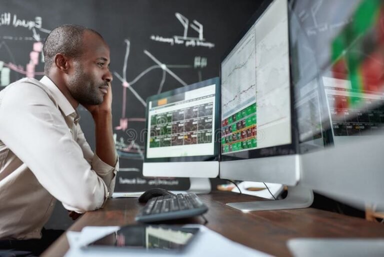 personne etudiant devant plusieurs ecrans financiers