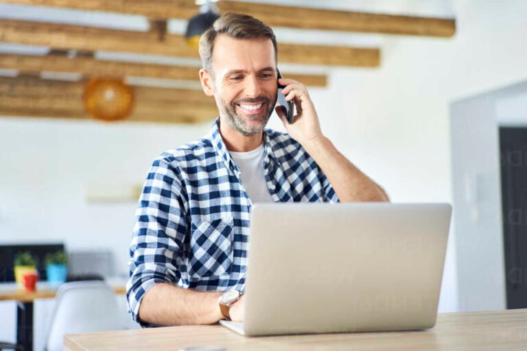 personne souriante au telephone avec ordinateur