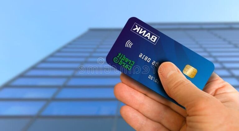 personne tenant une carte bancaire devant banque